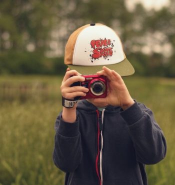 chłopiec wykonuje zdjęcie fotografowi małym czerwonym aparatem cyfrowym
