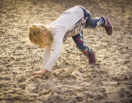 Dziewczynka wykonuje akrobacje na piasku